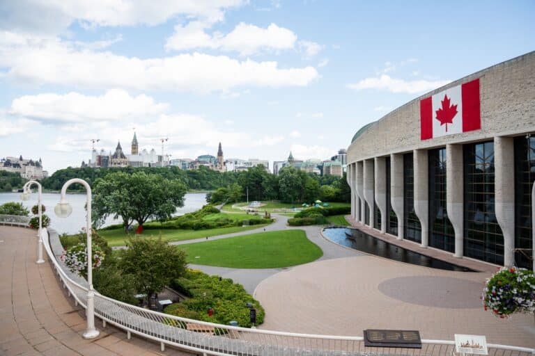 Canadian flag on a large building beside a river.